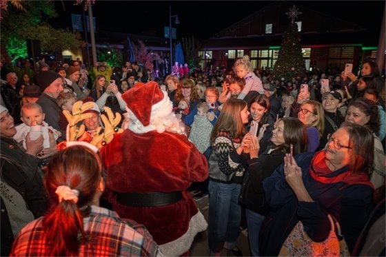 Santa at the tree lighting surrounded by a large group.